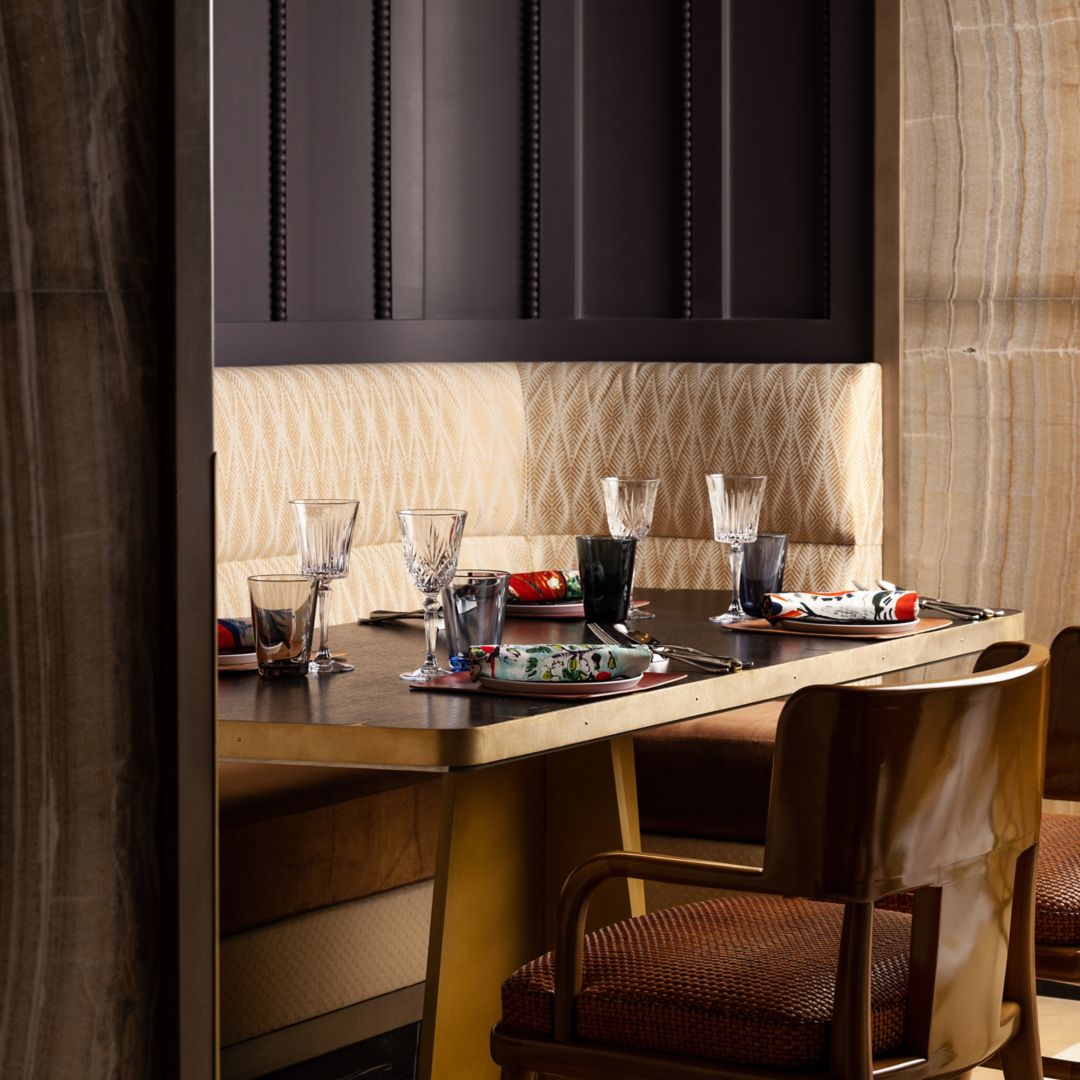 A dining booth with a table elegantly set with fine glassware and plates.